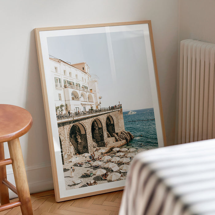 Framed photography print of a Amalfi Coast scene with buildings and ocean on a wall.