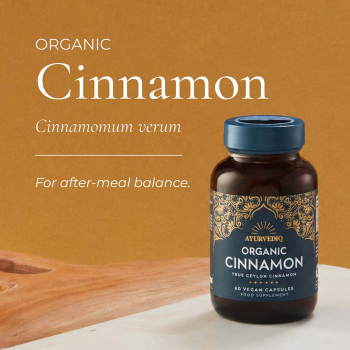 A bottle of Ayurveda Organic Cinnamon capsules on a light surface, with large text reading 'Organic Cinnamon' and smaller text 'For after-meal balance.'.