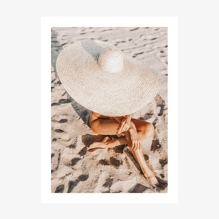 A photo wall art print featuring a woman on the beach wearing a Beach Hat in the sand