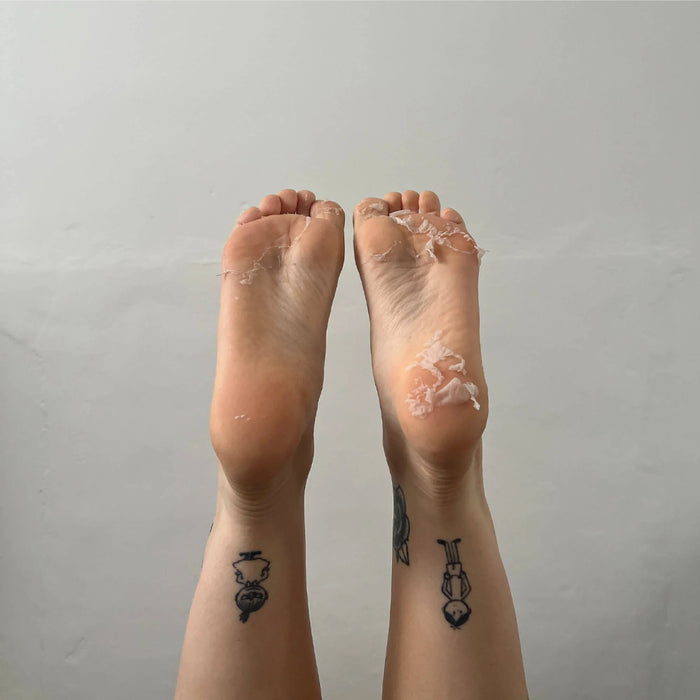 Two feet with clear plastic wrap on toes against a plain background