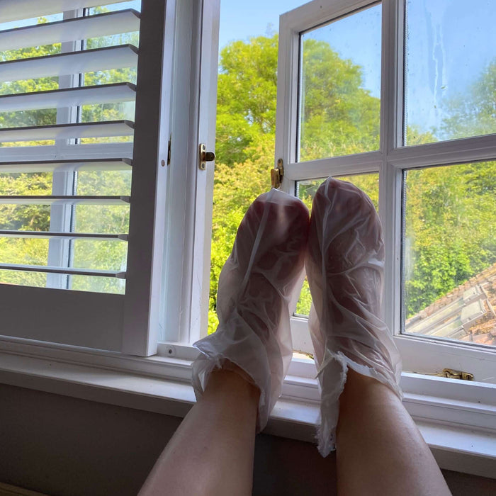 Feet in white lace socks by a window with greenery outside