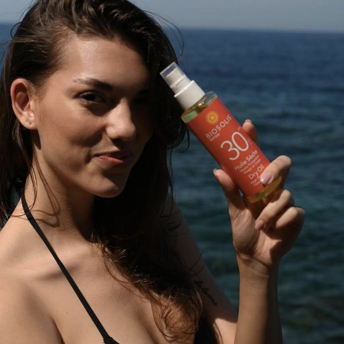 Girl at Beach holding BioSolis Sense Dry Oil Sense SPF30