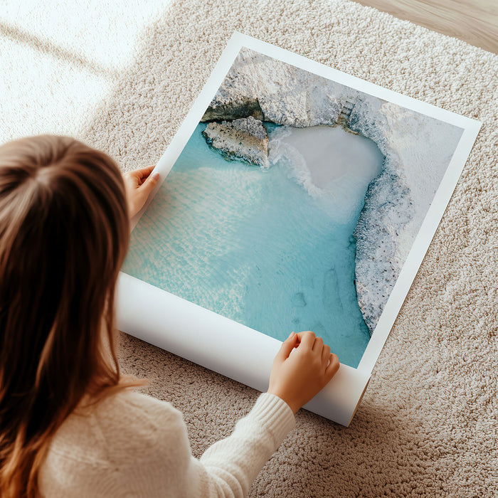 A woman unrolling a large photographic poster of a luxury scenic landscape on a carpeted floor