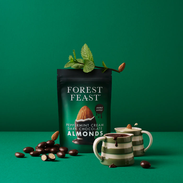 Packaging of Forest Feast Peppermint Cream Dark Chocolate Almonds with two mugs on a green background