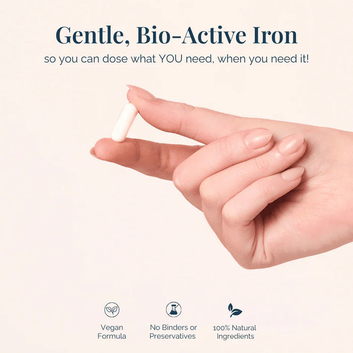 Hand holding a small iron supplement with promotional text about gentle, bio-active iron on a light background.