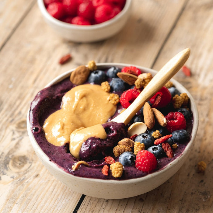 Berry smoothie bowl with toppings on a wooden surface