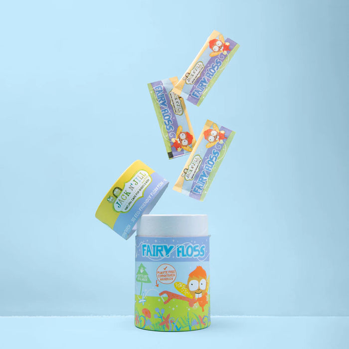 A colorful cylindrical container labeled 'FAIRY FLOSS' stands on a light blue surface with several matching floss packets floating above it against a pale blue background.