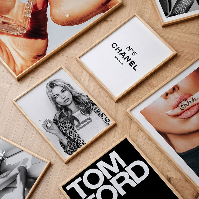 Collection of fashion wall art prints and framed posters on a wooden surface