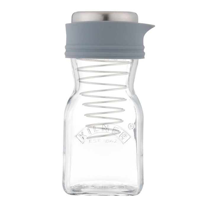 A clear glass spice jar with a grey silicone pour spout and lid, featuring a metal spring inside and the Kilder brand logo embossed on the front, set against a plain white background.