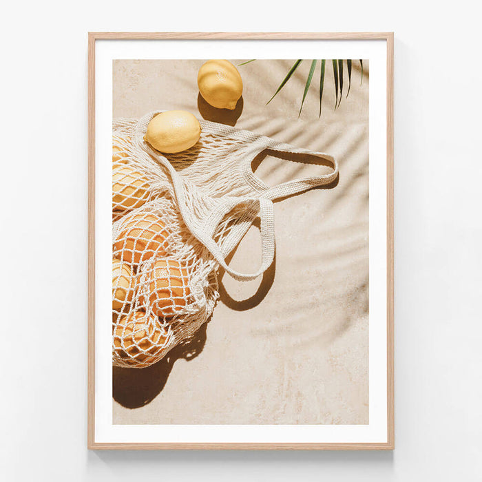 A framed photo wall art print featuring
Lemons in a bag on the beach