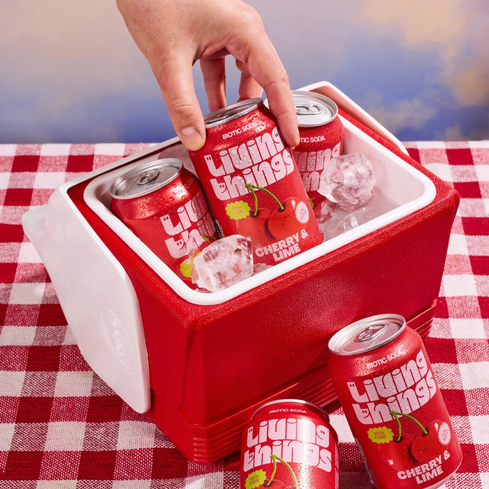 Red 'Living Things' cherry lime soda cans in a cooler on a red and white checkered tablecloth.
