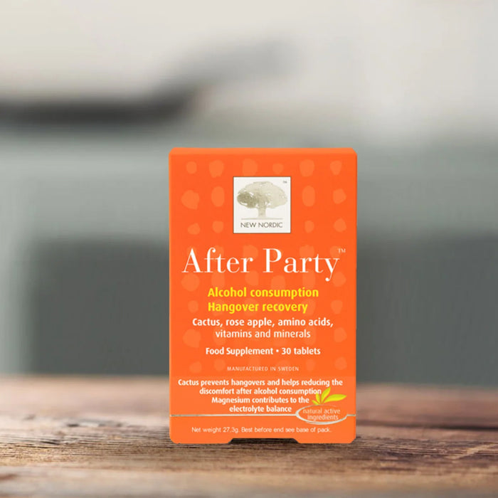 Orange supplement package labeled 'After Party' on a wooden surface with a blurred background