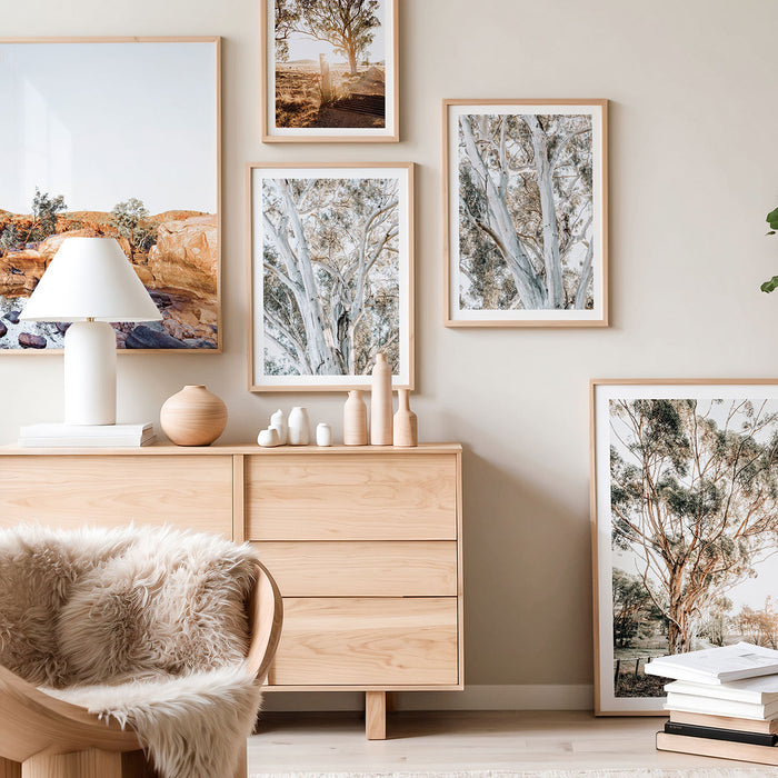 Wooden dresser with framed Australian landscape photography prints and decorative wall art items in a room setting.