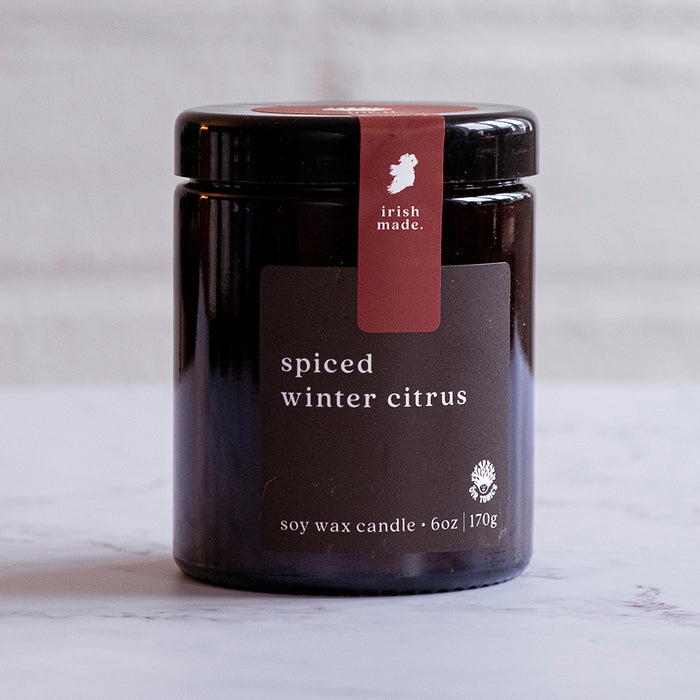A black jar candle with a label that reads 'spiced winter citrus', indicating it is a soy wax candle weighing 170g. Made In Ireland.