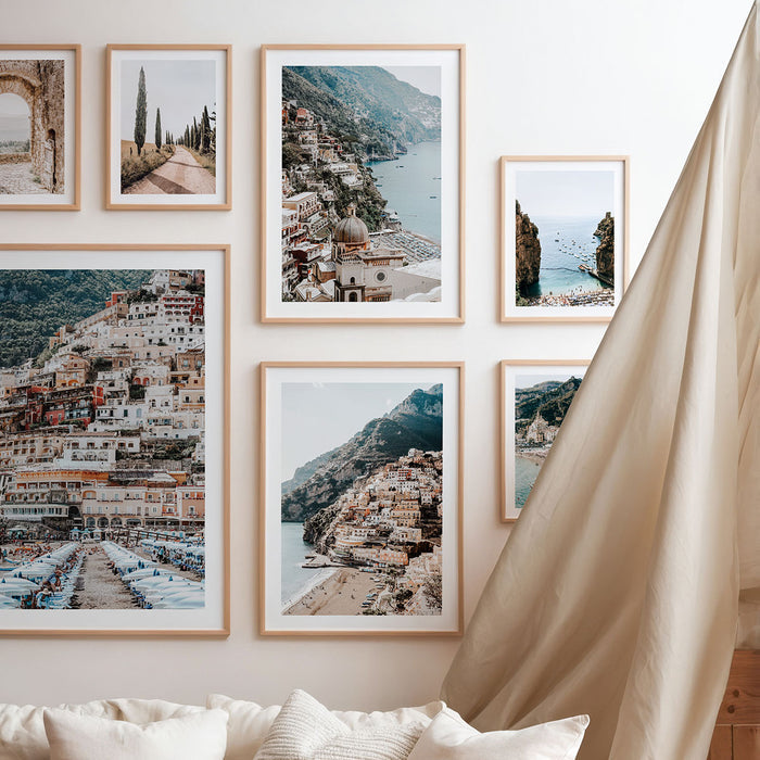 Framed photographic print of European coastal landscapes on a wall above a sofa in the style of a gallery.
