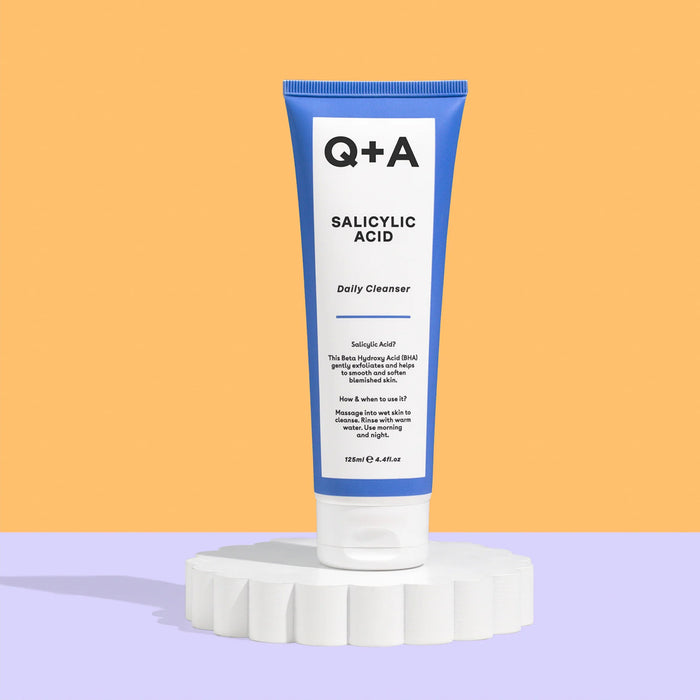 Tube of Q+A Salicylic Acid Daily Cleanser on a colorful background