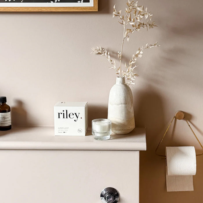 Bathroom counter with a vase, candle, and toiletries against a beige wall.