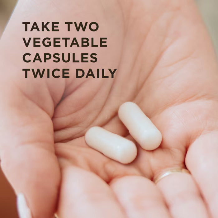 A close-up of a person's open palm holding two white oval capsules