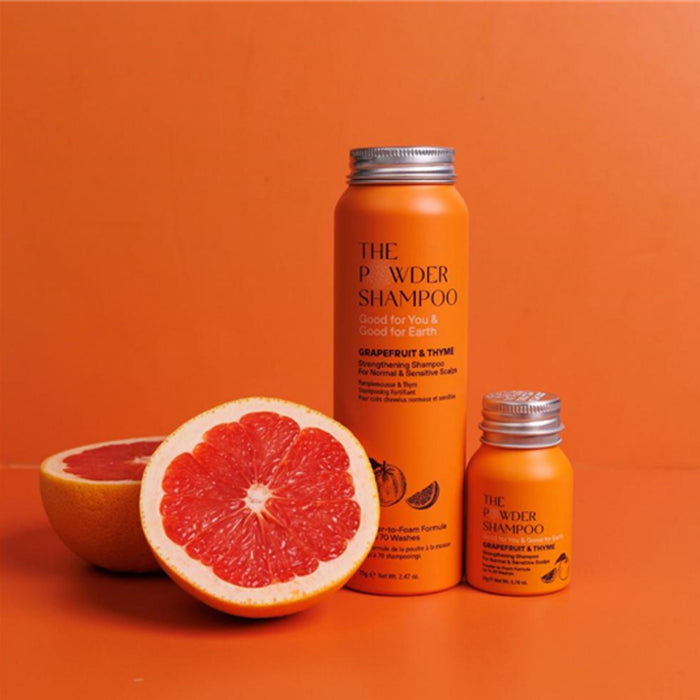 Orange shampoo bottles with grapefruit on an orange background