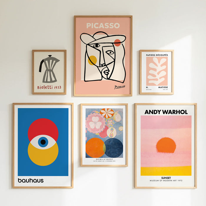 Collection of framed posters arranged on a gallery wall, featuring famous artists like Picasso, bauhaus and AndyWarhol.