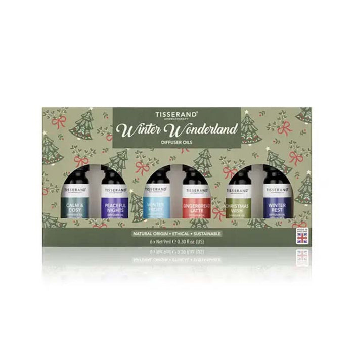 Tisserand 'Winter Wonderland' diffuser oils gift set in a decorative green box with Christmas tree illustrations. The set contains six essential oils in blue, purple, light blue, red, and green bottles, displayed against a clean white background with a soft reflection.