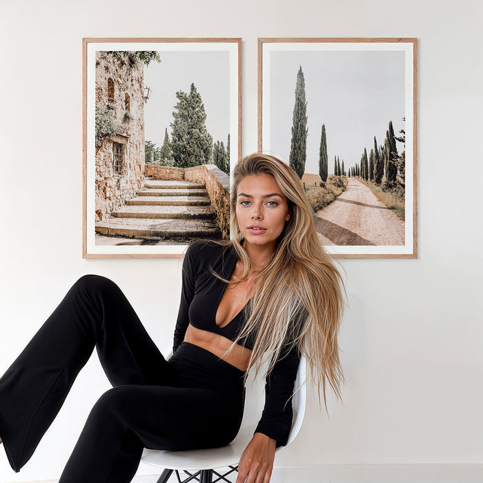Woman sitting on a chair in a room with two framed photographic prints on the wall from Tuscany Italy.