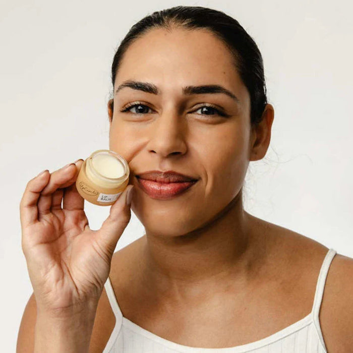 Woman holding a jar of UpCircle Lip Balm against a white background