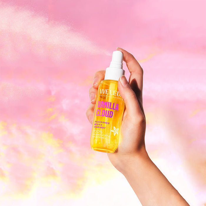A hand holding a spray bottle of WELEDA Vanilla Cloud Fragrance Mist.