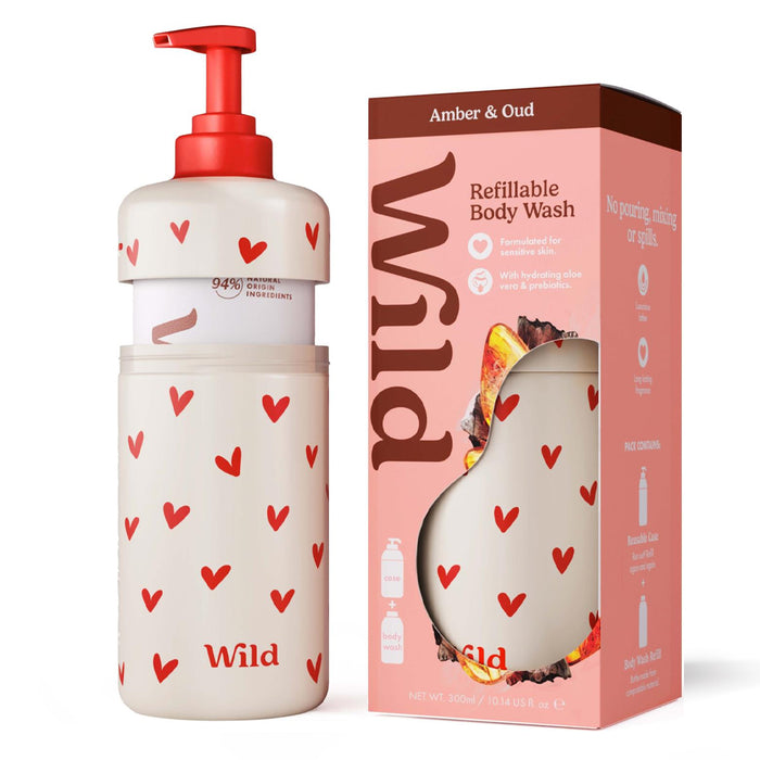 A refillable Wild Amber & Oud Refill Body Wash bottle with a red pump and red heart pattern next to its pink retail box labeled Wild Amber & Oud.