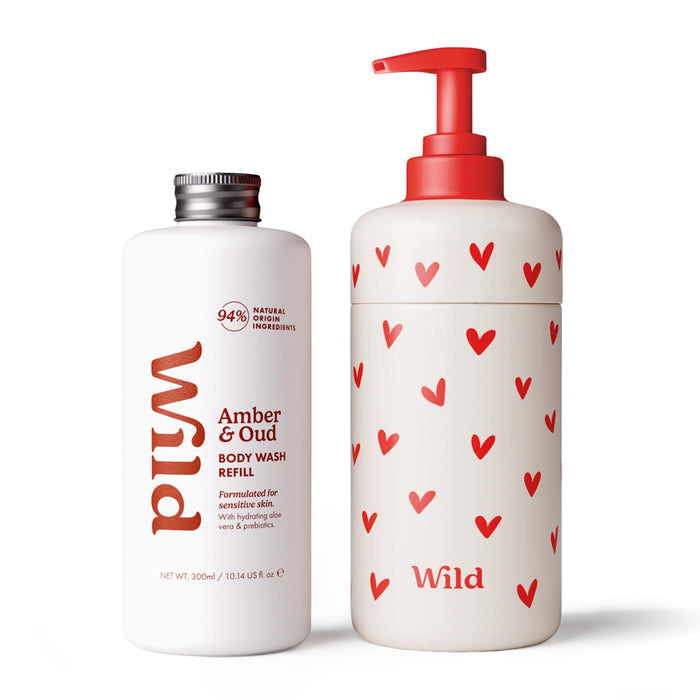 Wild Amber & Oud body wash refill set featuring a 300ml white bottle with a silver cap and a matching white pump bottle decorated with red hearts, both on a white background.