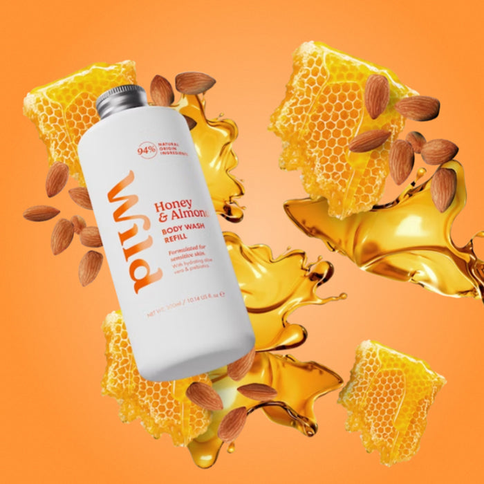 A white bottle of Wild Honey & Almond Body Wash Supernova floating over a stylized orange background with honeycomb, almonds, and golden honey splashes.