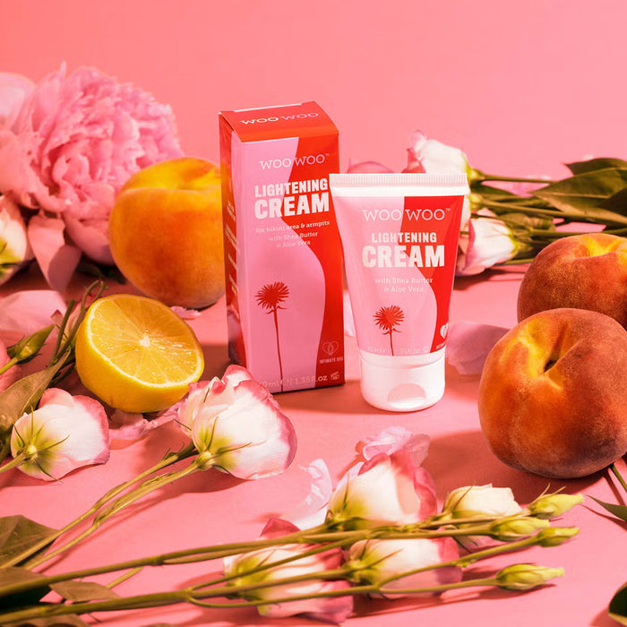 Woo Woo lightening cream with packaging on a pink background with peaches and flowers.