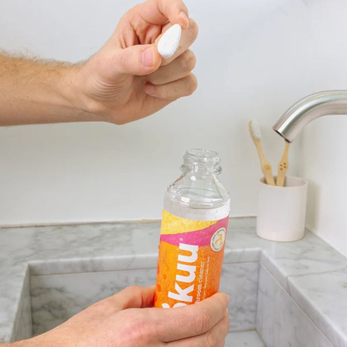 Person holding a bottle of Iskku water over a sink.