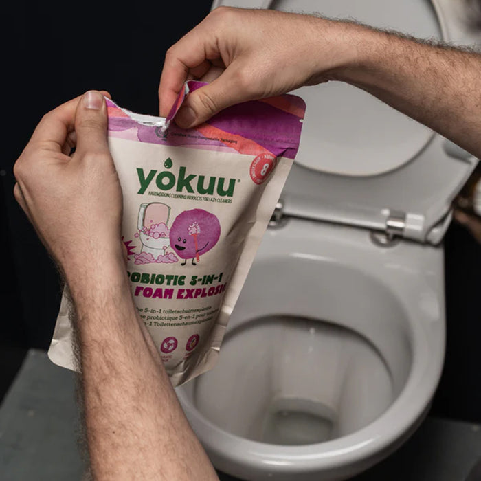 Person holding a 'yokuu' product package in front of a toilet.