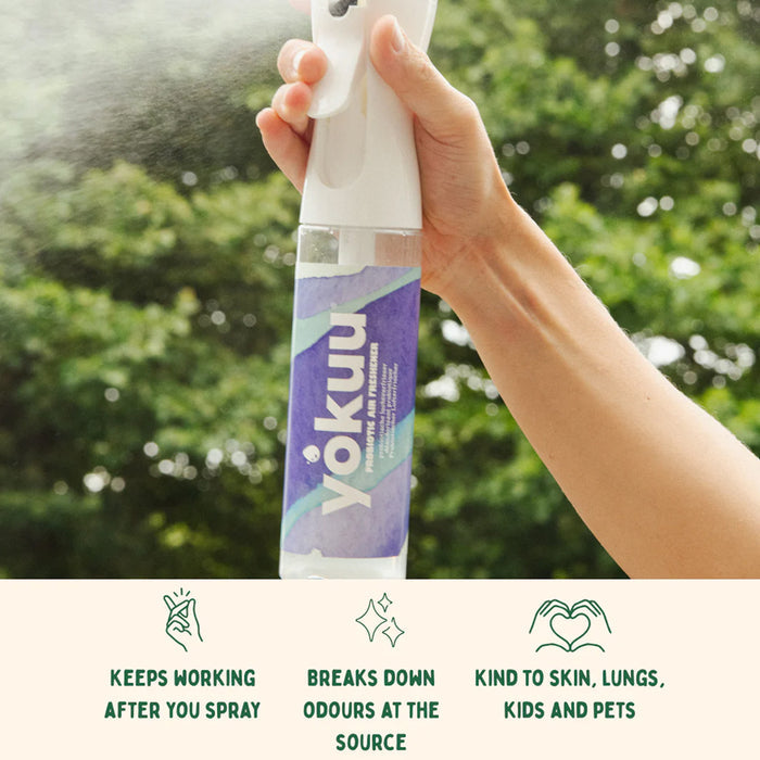 Hand holding a Yokuu spray bottle with greenery in the background
